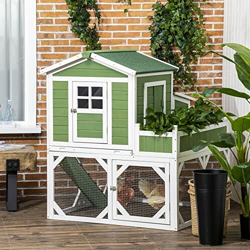 Green wooden rabbit hutch with plants and outdoor setup.